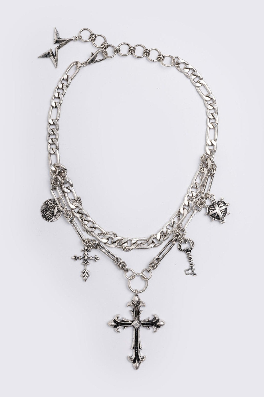 Silver chunky layered necklace featuring cross, key and medallion pendants.