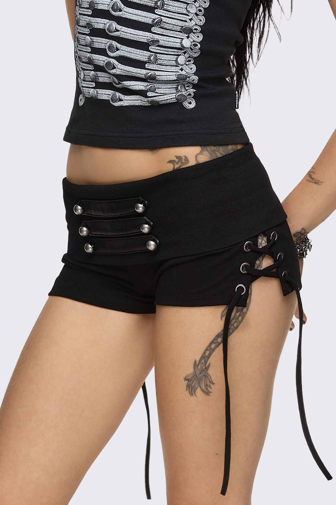 Black hot pants with lace-up sides, faux leather straps, silver dome buttons and a wide fold-over waistband.