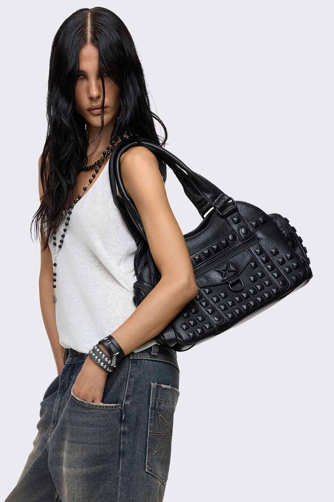 Black faux leather shoulder bag with pyramid studs, front zip pocket, side pockets and two top handles.
