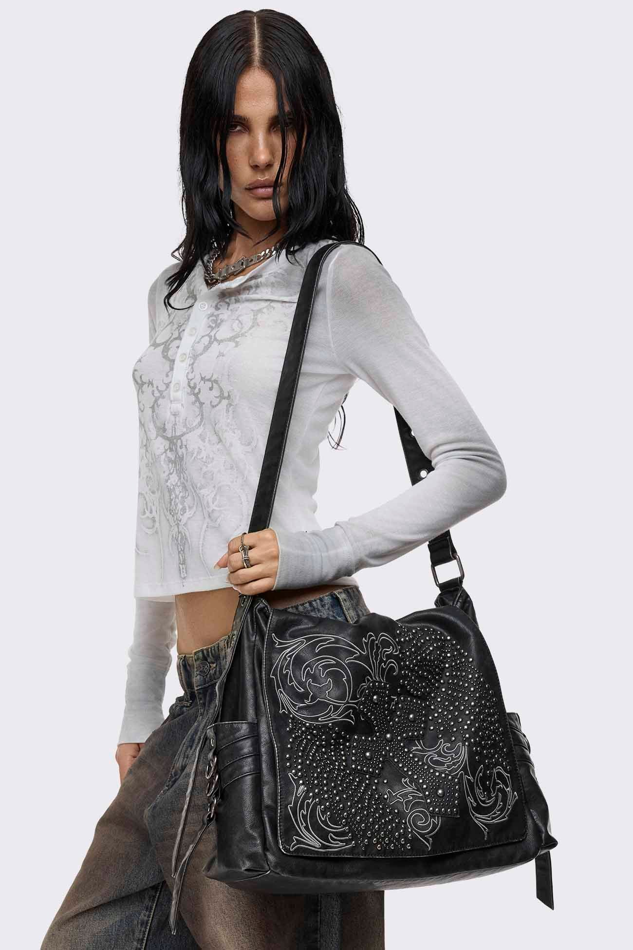 Black faux leather messenger bag with studded cross design, embroidered detail, fold-over flap and adjustable strap.