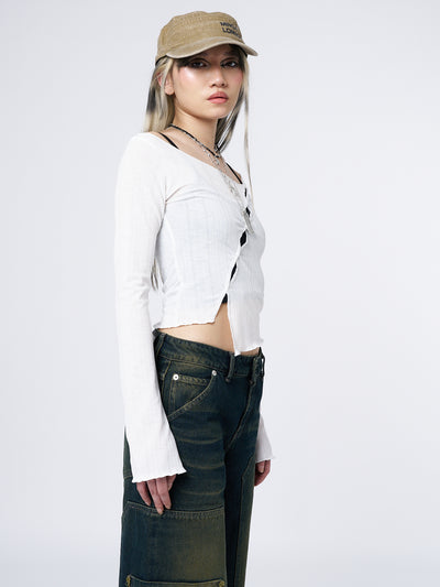 Edgy and stylish long sleeve top in white with asymmetrical cut-out details. Perfect for a trendy and daring grunge-inspired look.