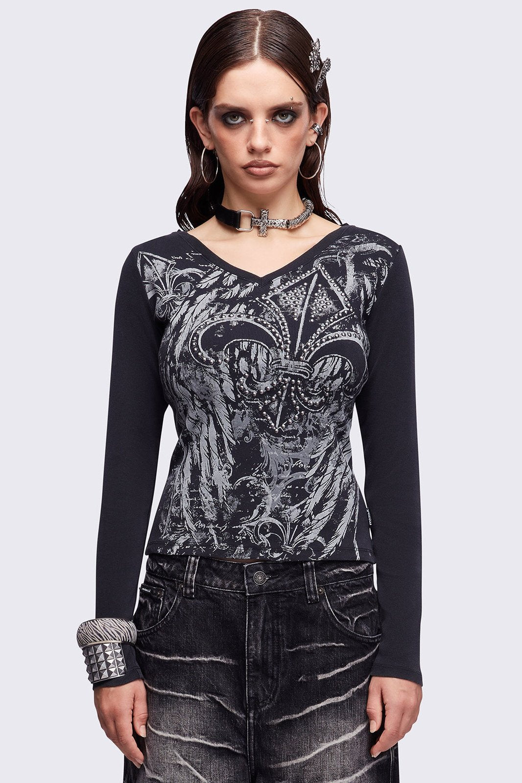 Black washed v-neck ribbed top featuring a fleur-de-lis graphic front print and silver stud details.