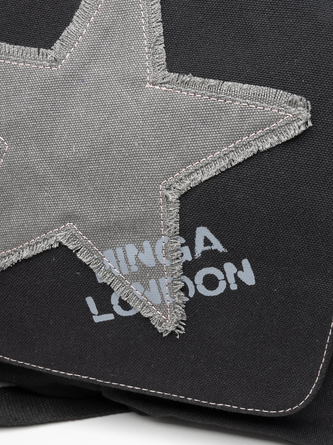 Black canvas messenger bag by Minga London. Featuring a Super Star design. Stylish and practical accessory for carrying essentials with flair.