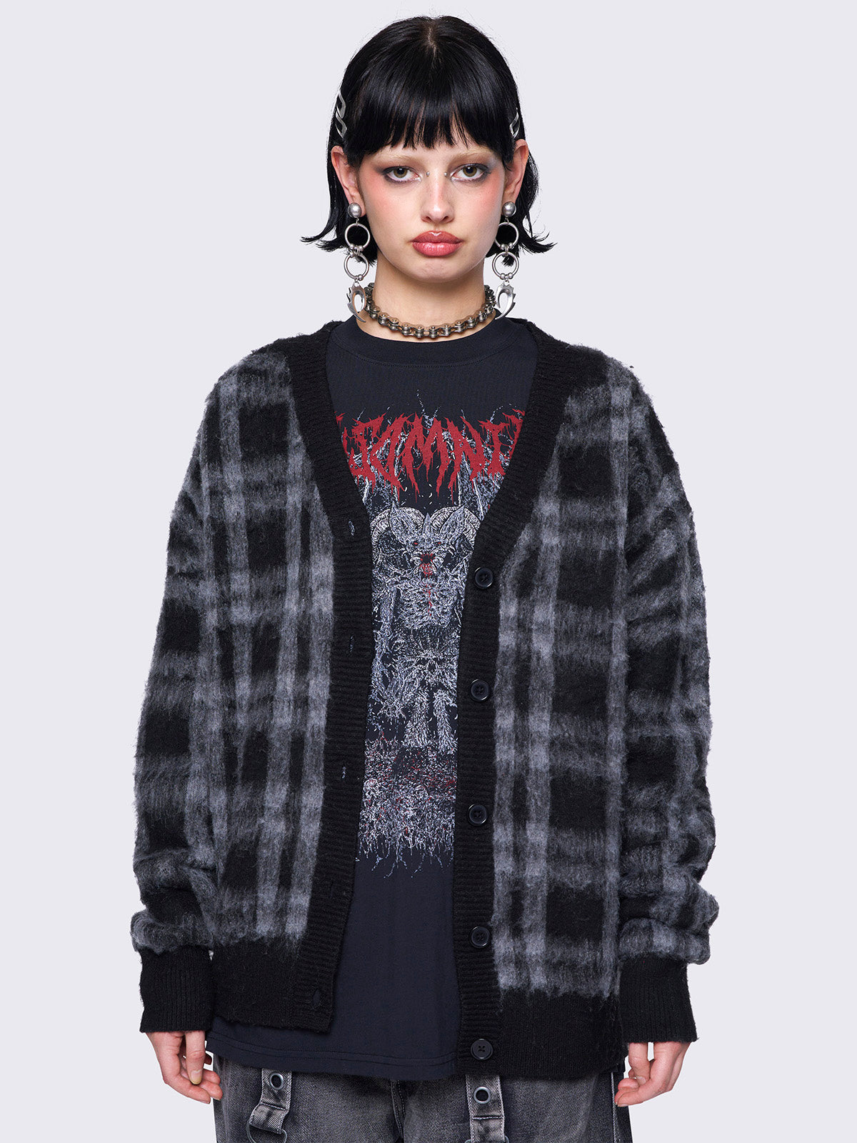 Black and grey plaid oversized cardigan, featuring a soft fuzzy texture and button-down front, paired with graphic t-shirt for an alternative fashion look.