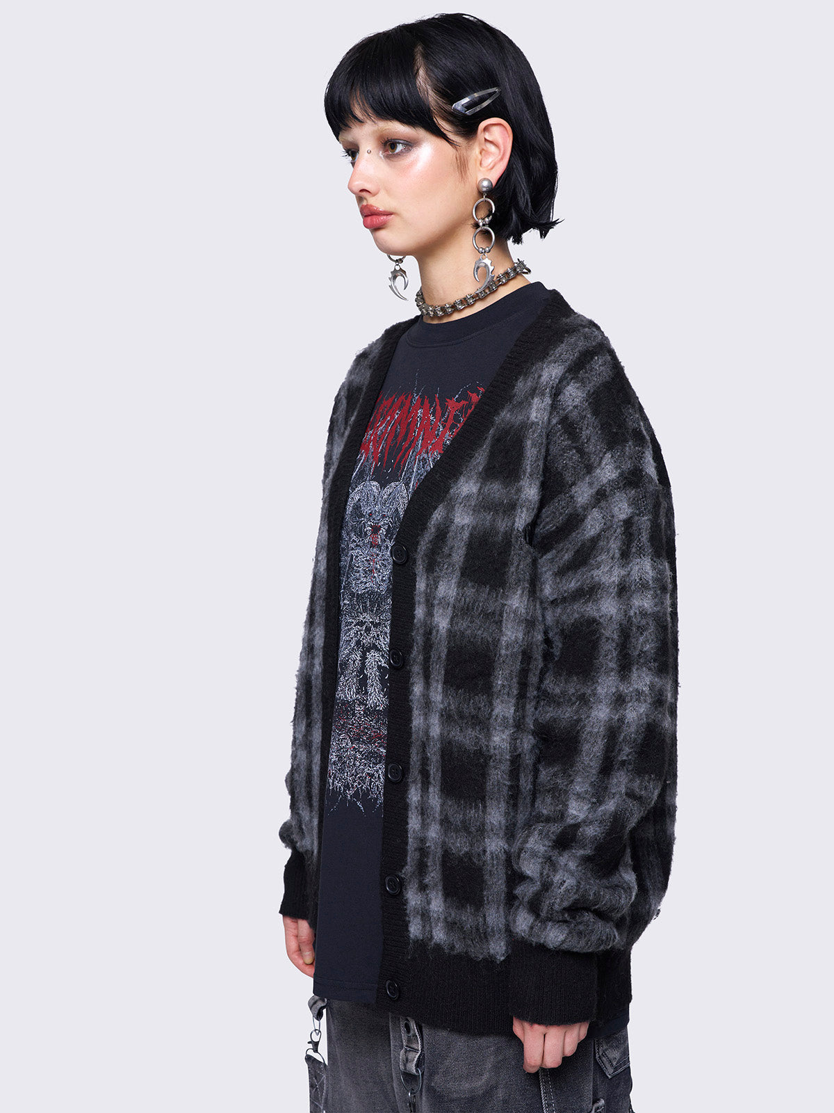 Black and grey plaid oversized cardigan, featuring a soft fuzzy texture and button-down front, paired with graphic t-shirt for an alternative fashion look.