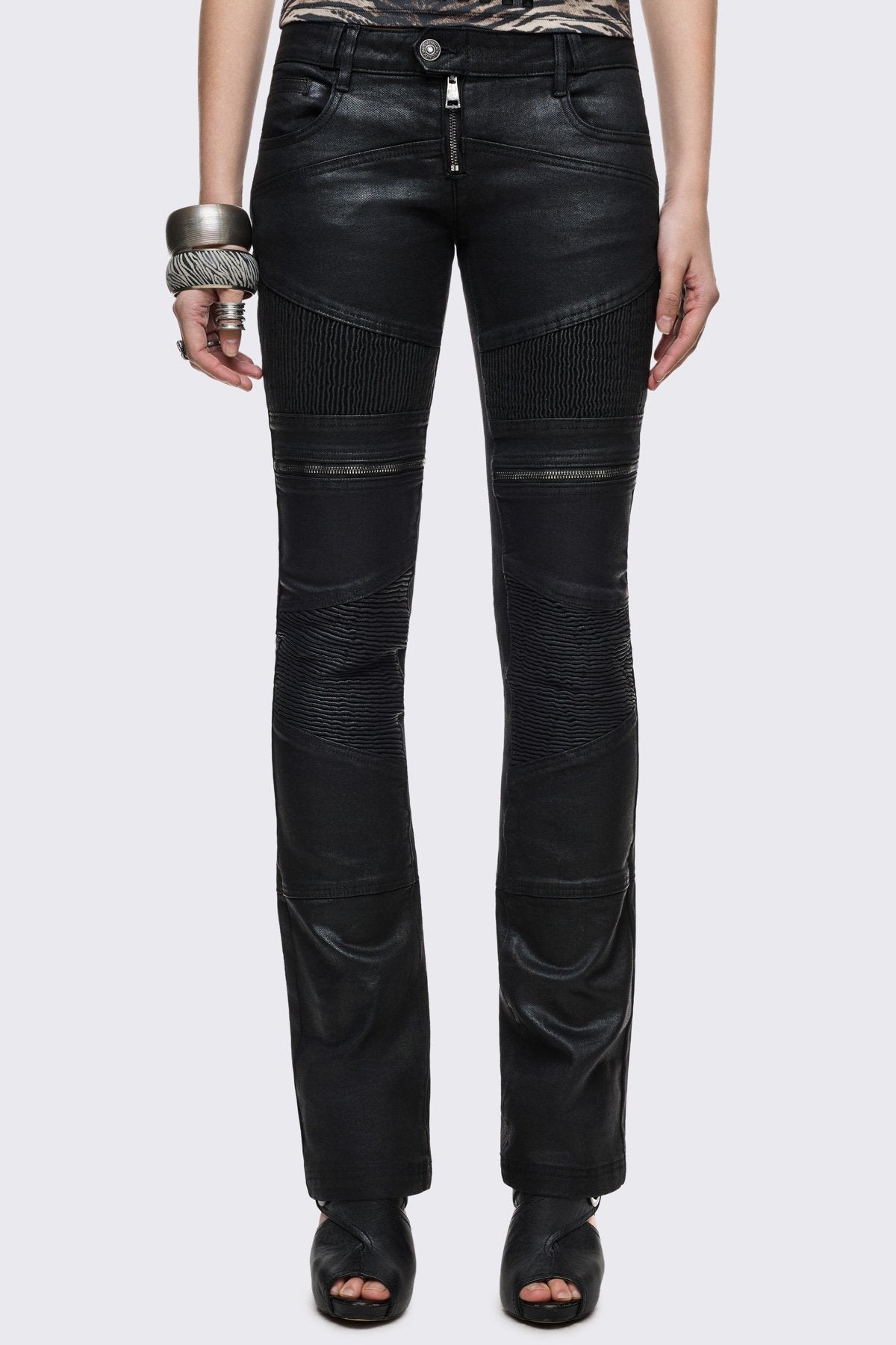 Bootcut jeans in black coated denim with ribbed paneling and zipper details, low-rise grunge aesthetic.