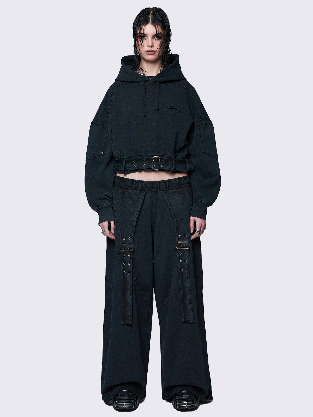 Cropped washed black hoodie with a detachable buckle belt at the hem, an embroidered logo on the chest, raglan sleeves, and a drawstring hood. Stylish and comfortable.