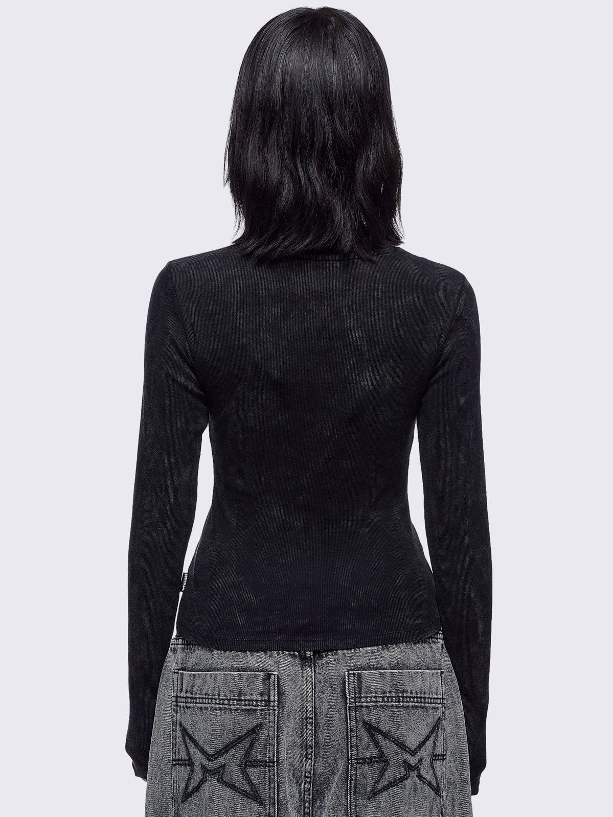 Black washed asymmetric top with cut-out and safety pin details.