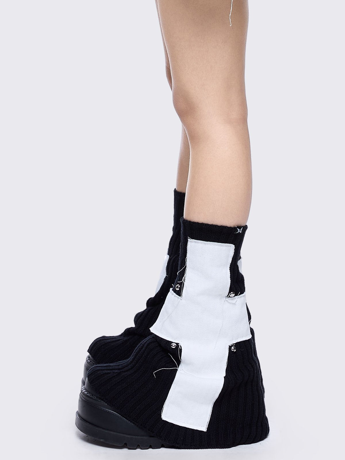 Black knitted flare leg warmers featuring a white chunky cross patch 