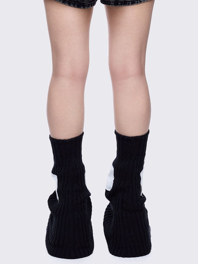 Black knitted flare leg warmers featuring a white chunky cross patch 