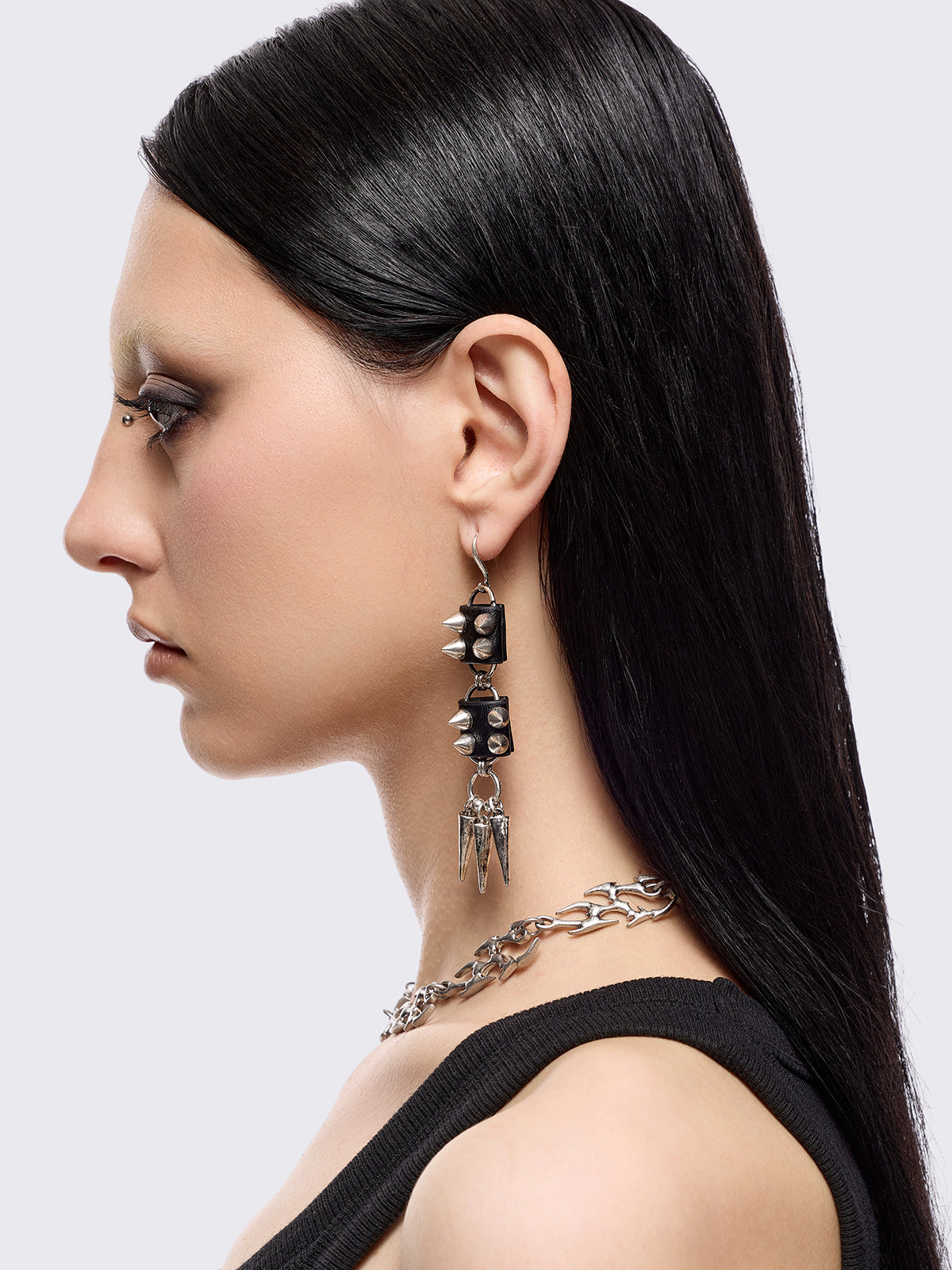 Silver dangle earrings with spiked pendants and black faux leather details
