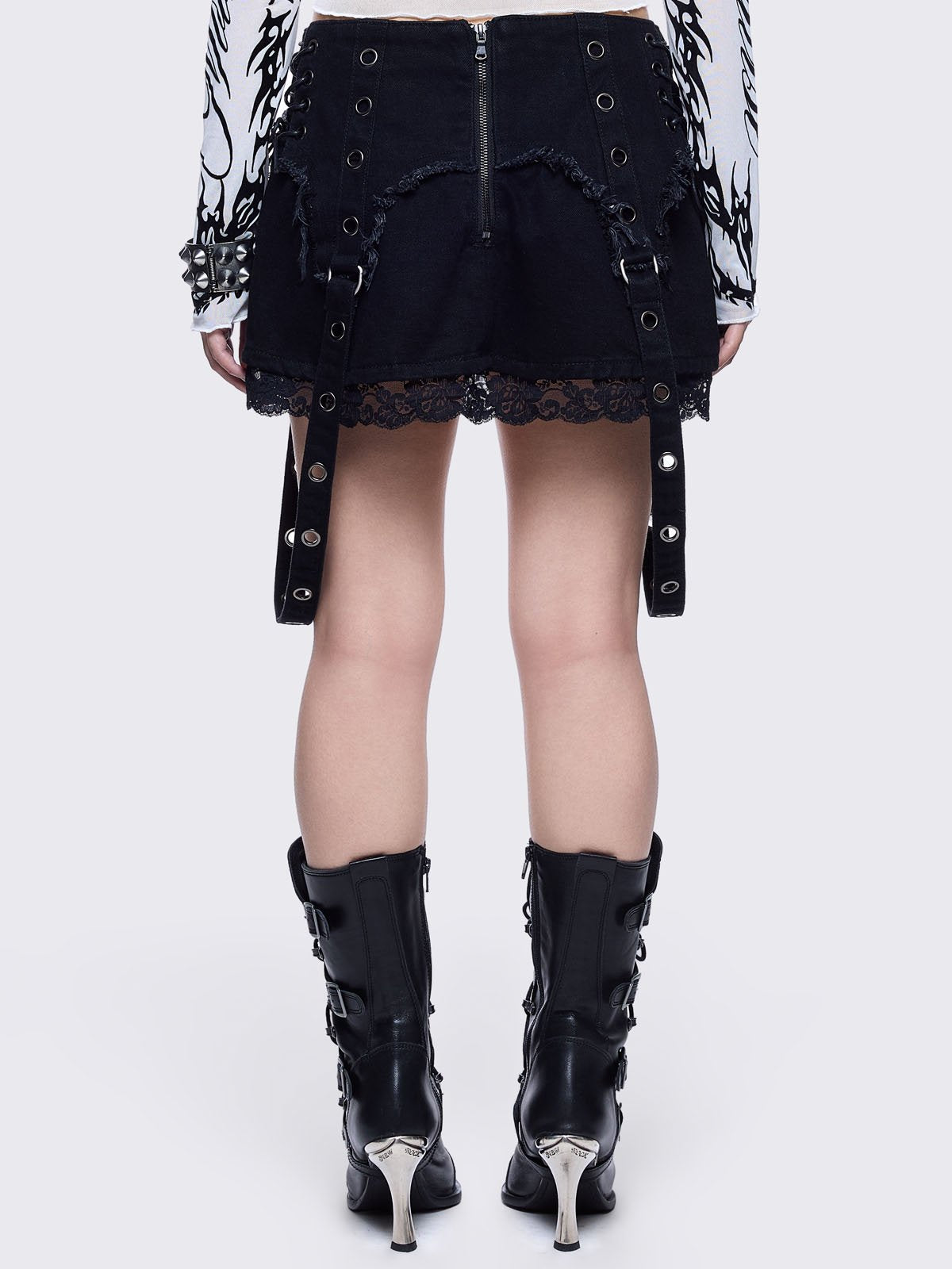 Black denim mini skirt with distressed frayed panels, lace up side details and eyelet straps.