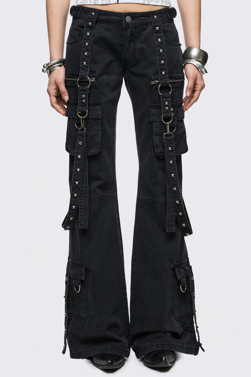 Black cotton cargo jeans with flared leg, studded straps, zip pockets and D-ring details in a goth Y2K style.
