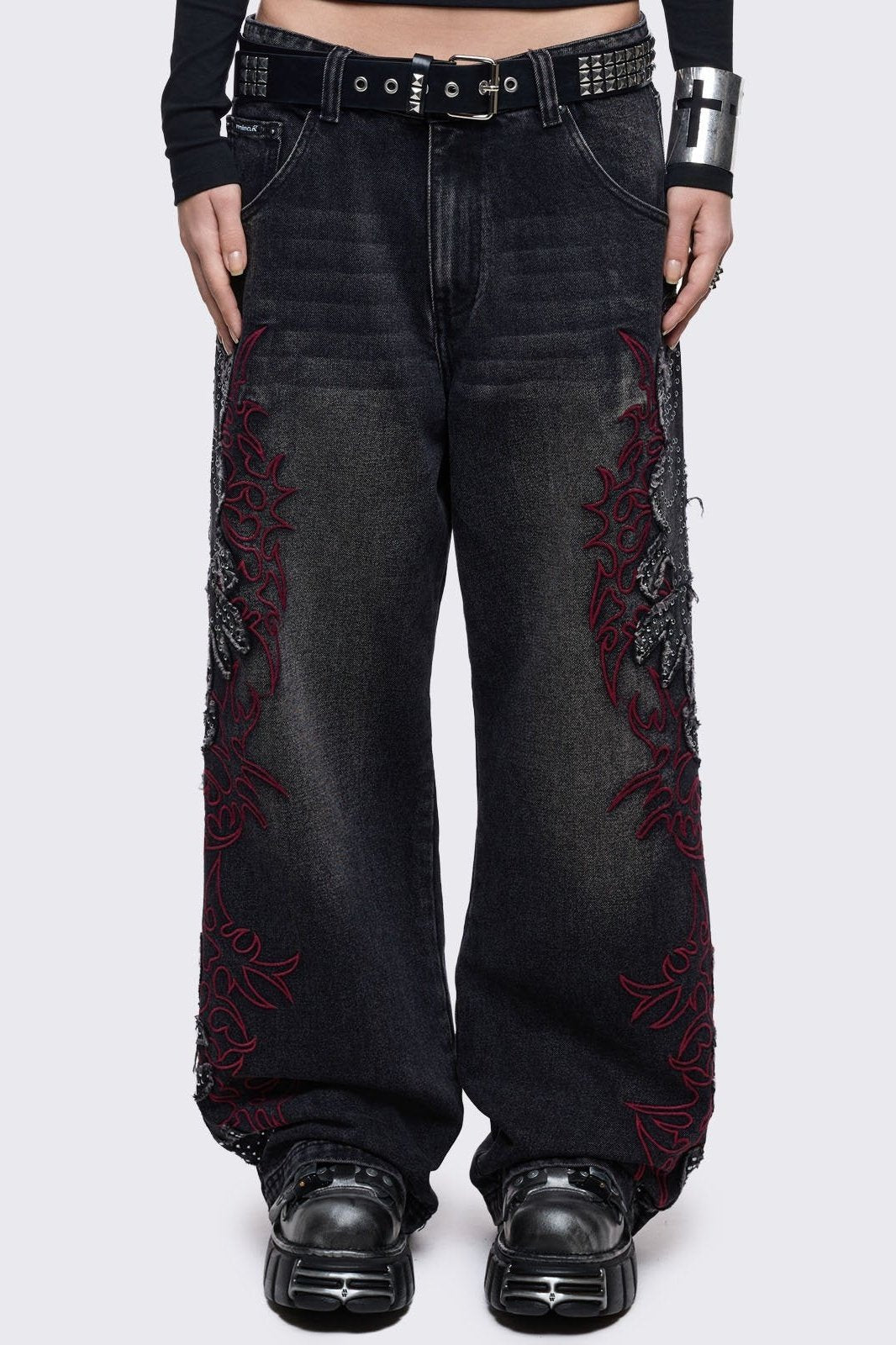 Black washed baggy jeans with grey overdye, frayed patches with silver studs and red sigilism embroideries. 