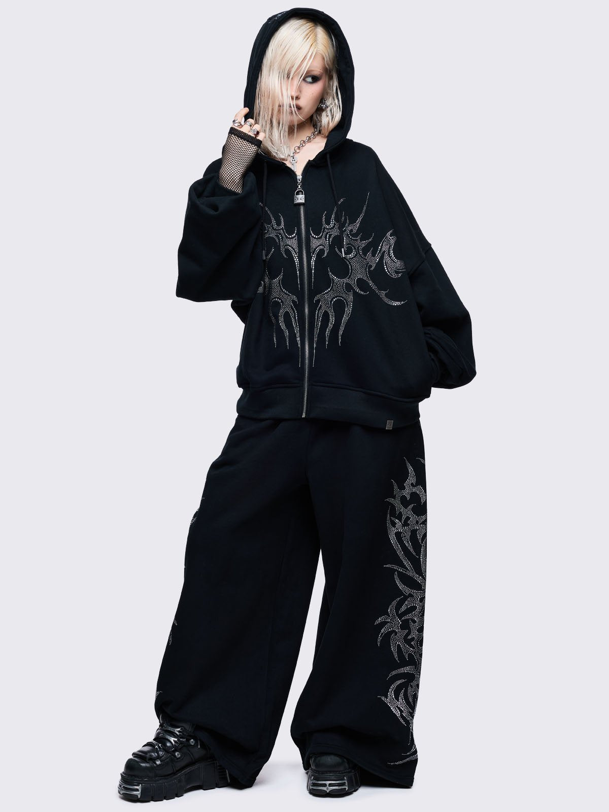 Loose-fit wide-leg sweatpants featuring a large, detailed tribal sigil pattern made of silver rhinestones running down the side seam.