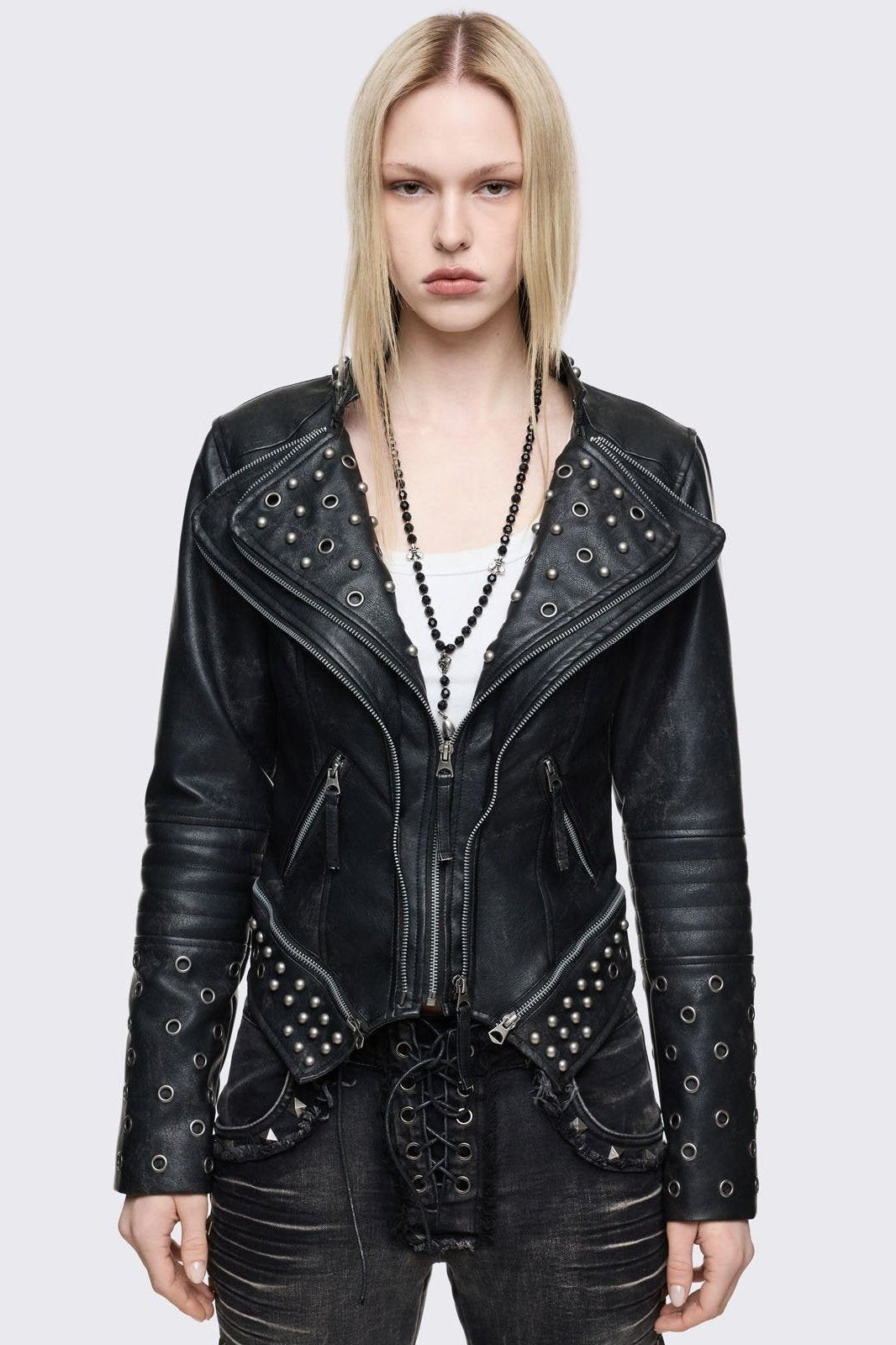 Black faux leather biker jacket with silver eyelet, stud and zip details. Pointed asymmetrical hem and large notched lapels.