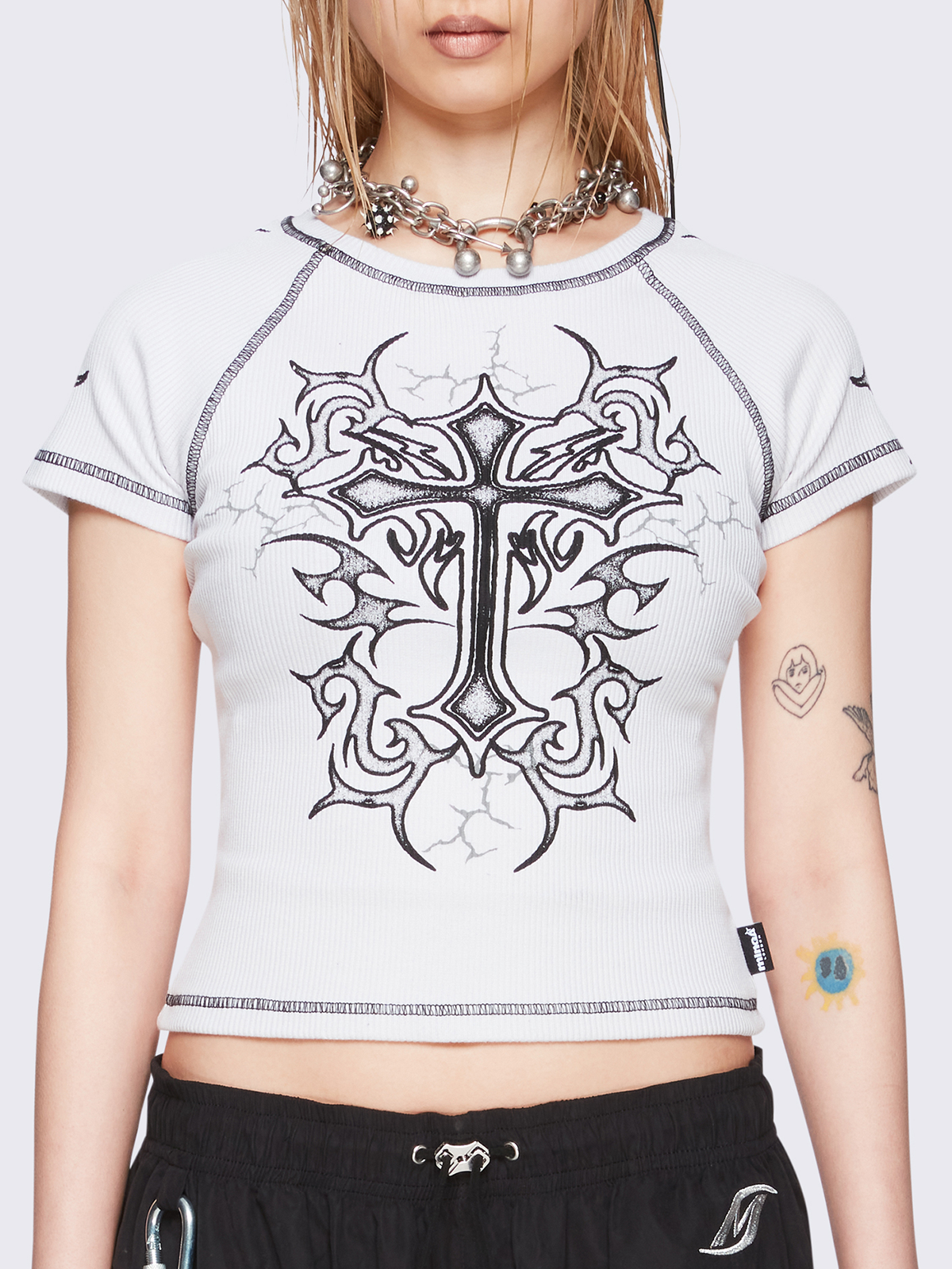 Off-white graphic raglan baby tee with tribal cross print and black contrast stitching.