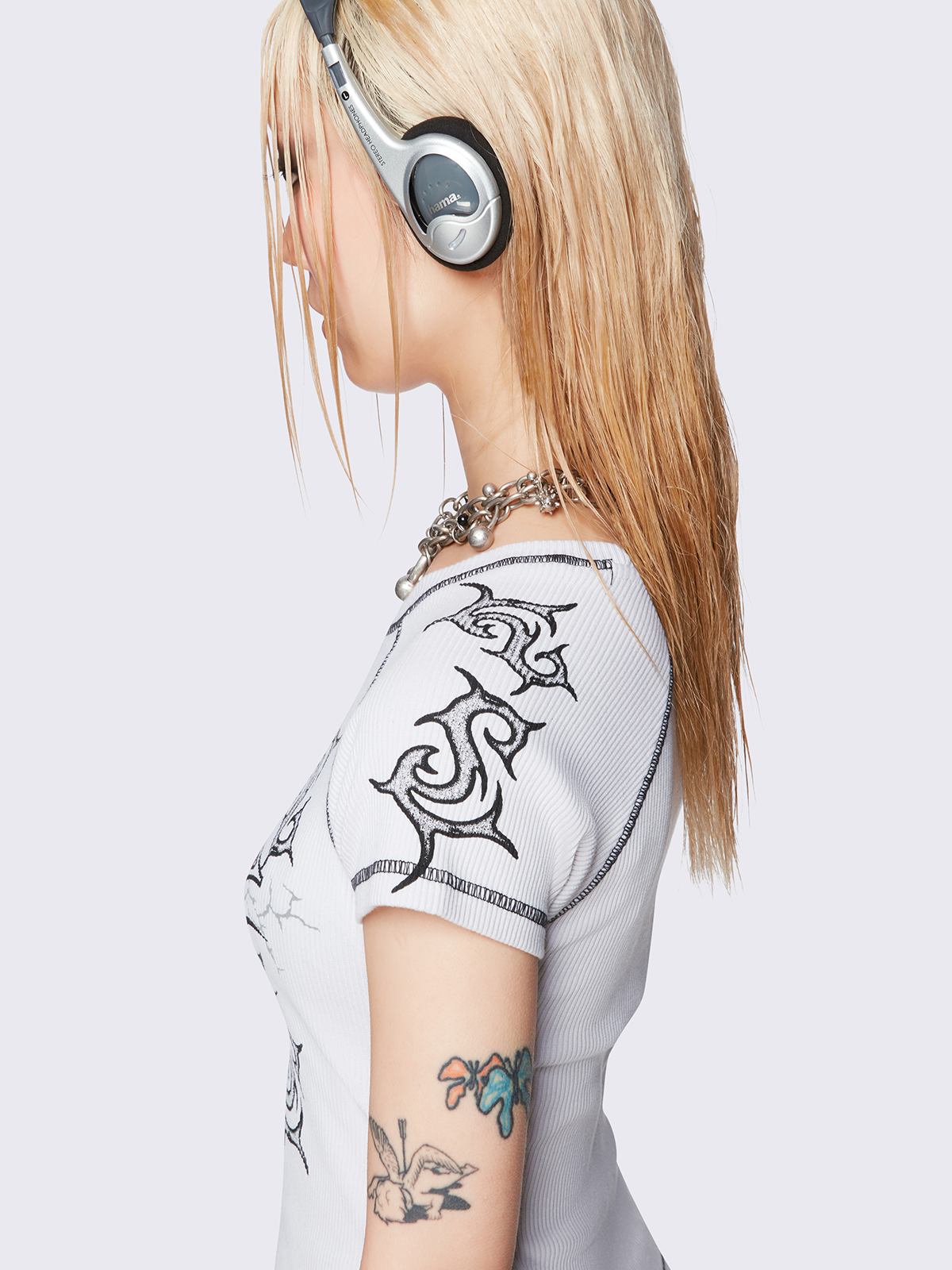 Off-white graphic raglan baby tee with tribal cross print and black contrast stitching.
