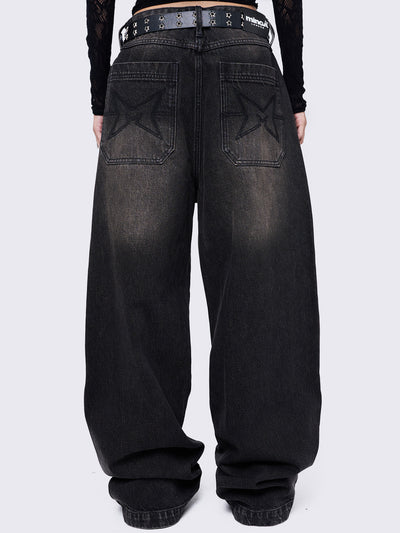 Black washed baggy jeans with brown overdye featuring a cross raw edge patches.