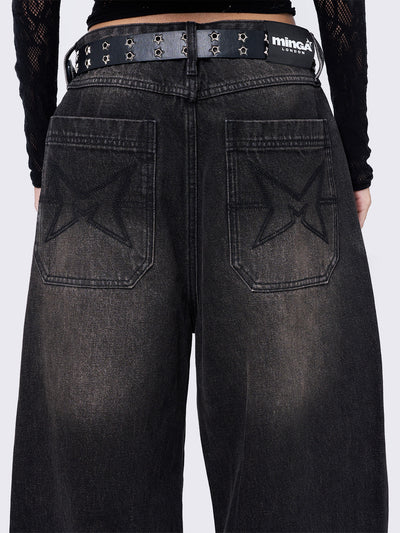 Black washed baggy jeans with brown overdye featuring a cross raw edge patches.