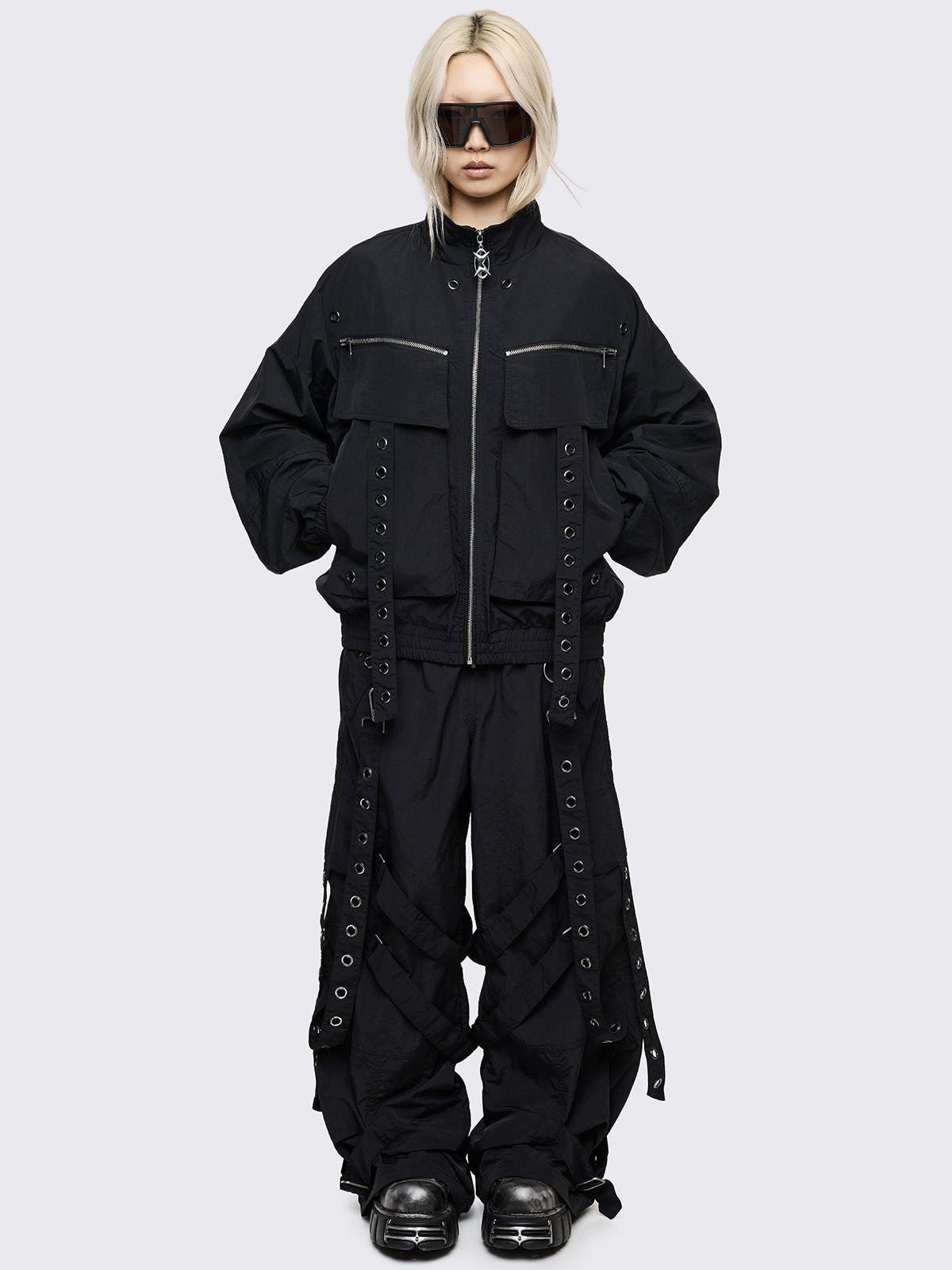 Black boxy oversized windbreaker jacket with straps and metal hardware details. 