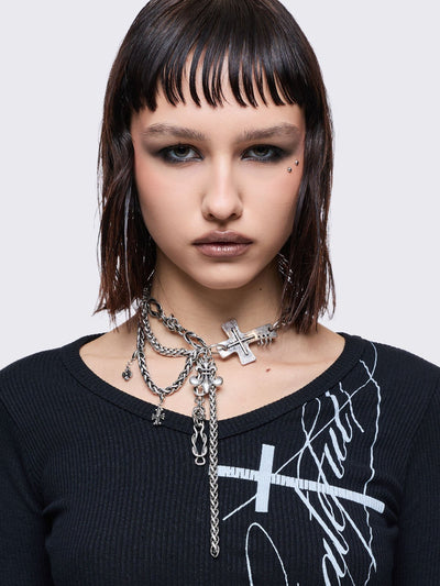 Layered necklace with chunky cross, fleur-de-lis and chain pendants.