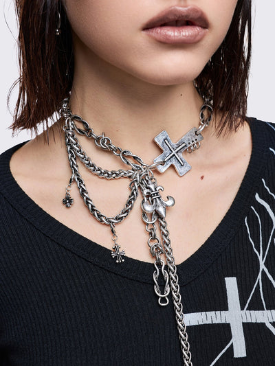 Layered necklace with chunky cross, fleur-de-lis and chain pendants.