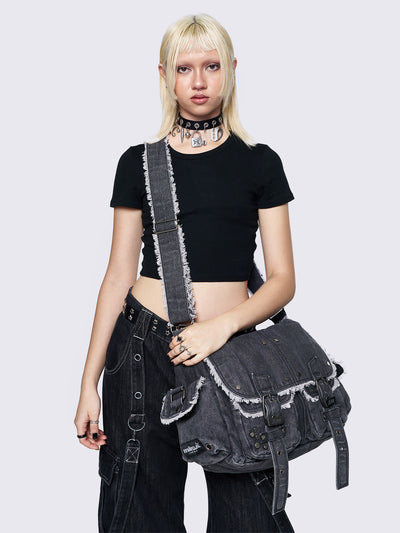 Black wash denim shoulder bag with frayed edges, flap closure, buckle straps, and studded details. Perfect for grunge and Y2K-inspired streetwear.