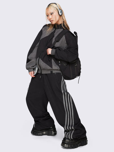 Black parachute pants with grey side stripes. 