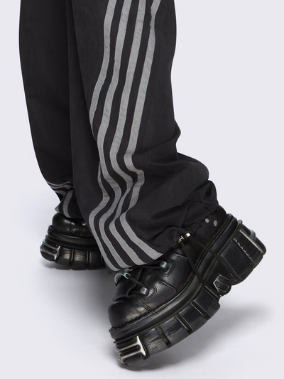 Black parachute pants with grey side stripes. 