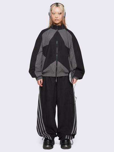 Black parachute pants with grey side stripes. 