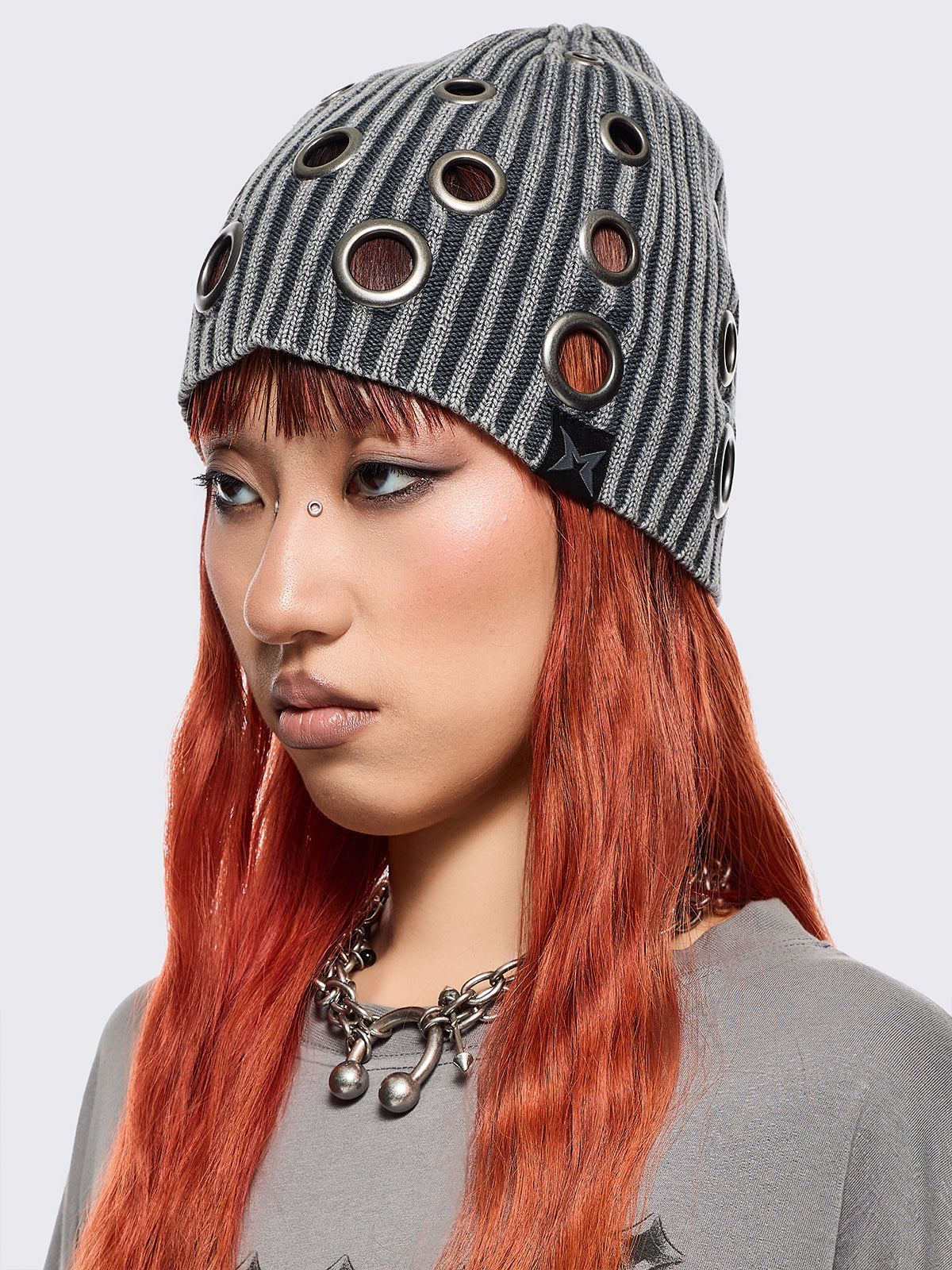 Grey ribbed knit beanie with chunky silver eyelets.