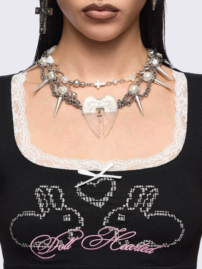 Chunky silver charm necklace with spike, pearl, piercing and cross details and a chunky angel wings pendant.