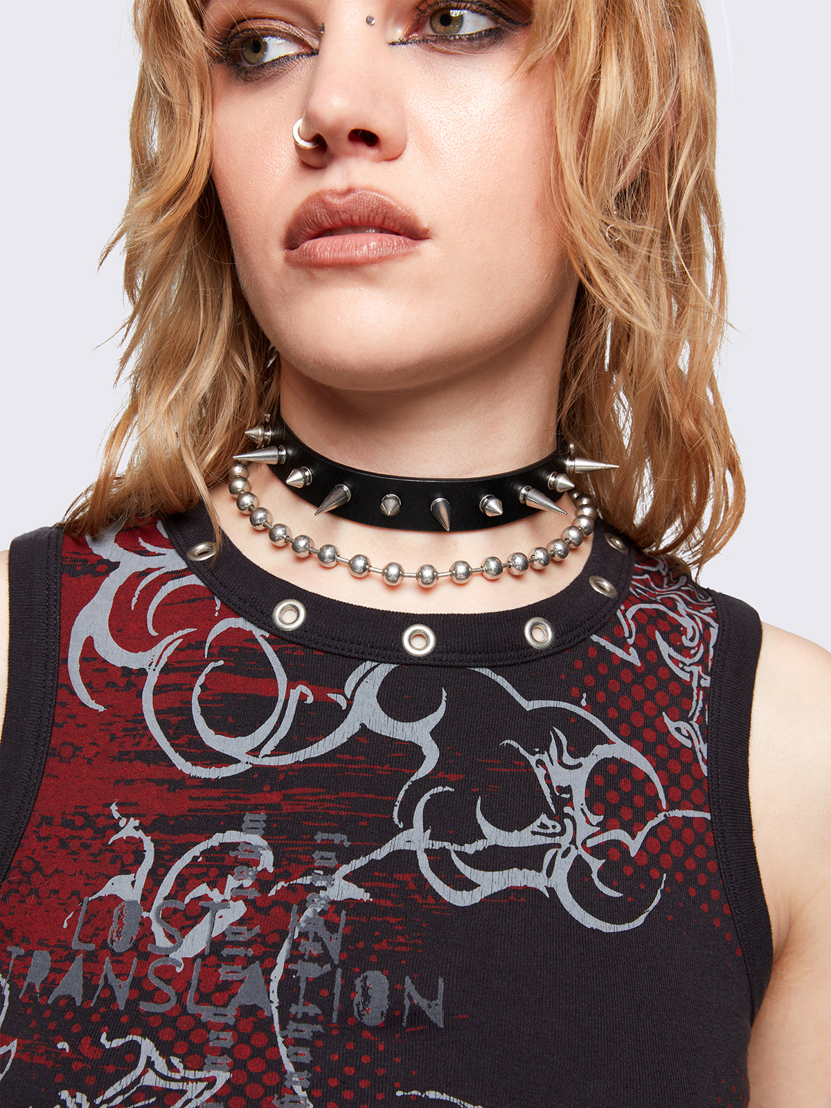 Black tank top with red and grey grunge graphic front print and eyelet details at neckline. Vest and sleeveless style.