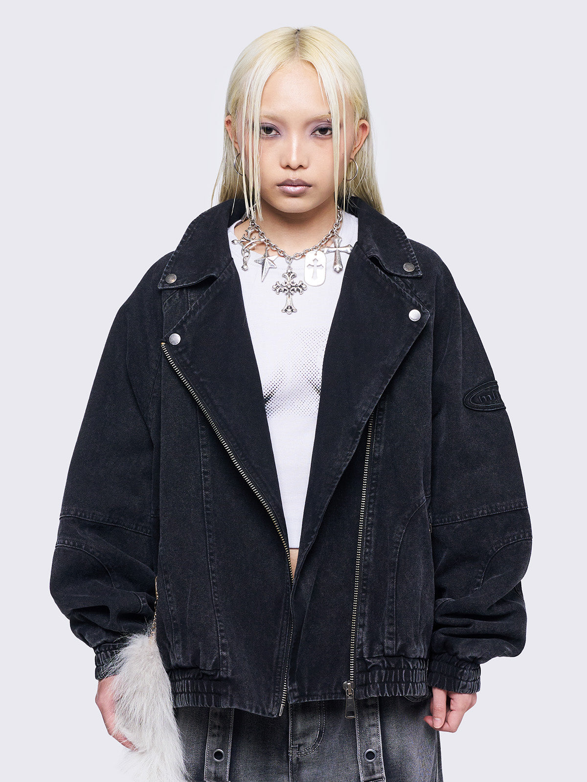 Black washed twill bomber jacket with wide lapel collar, asymmetric zip closure, oversized fit, and seam details. Features an elasticated hem, cuffs, side pockets, and an embroidered sleeve patch.