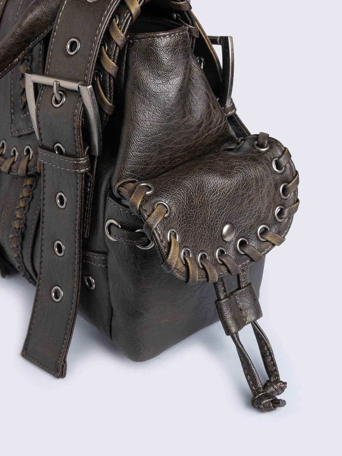 Brown faux leather shoulder bag featuring lace ups, eyelets, buckles and multiple pockets.