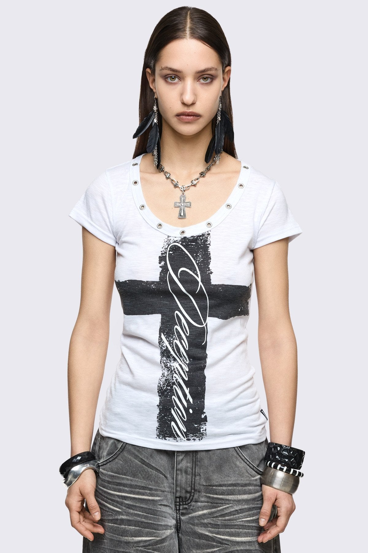 White baby tee in stretch jersey with black cross graphic, scoop neck eyelet details, and grunge vibe.