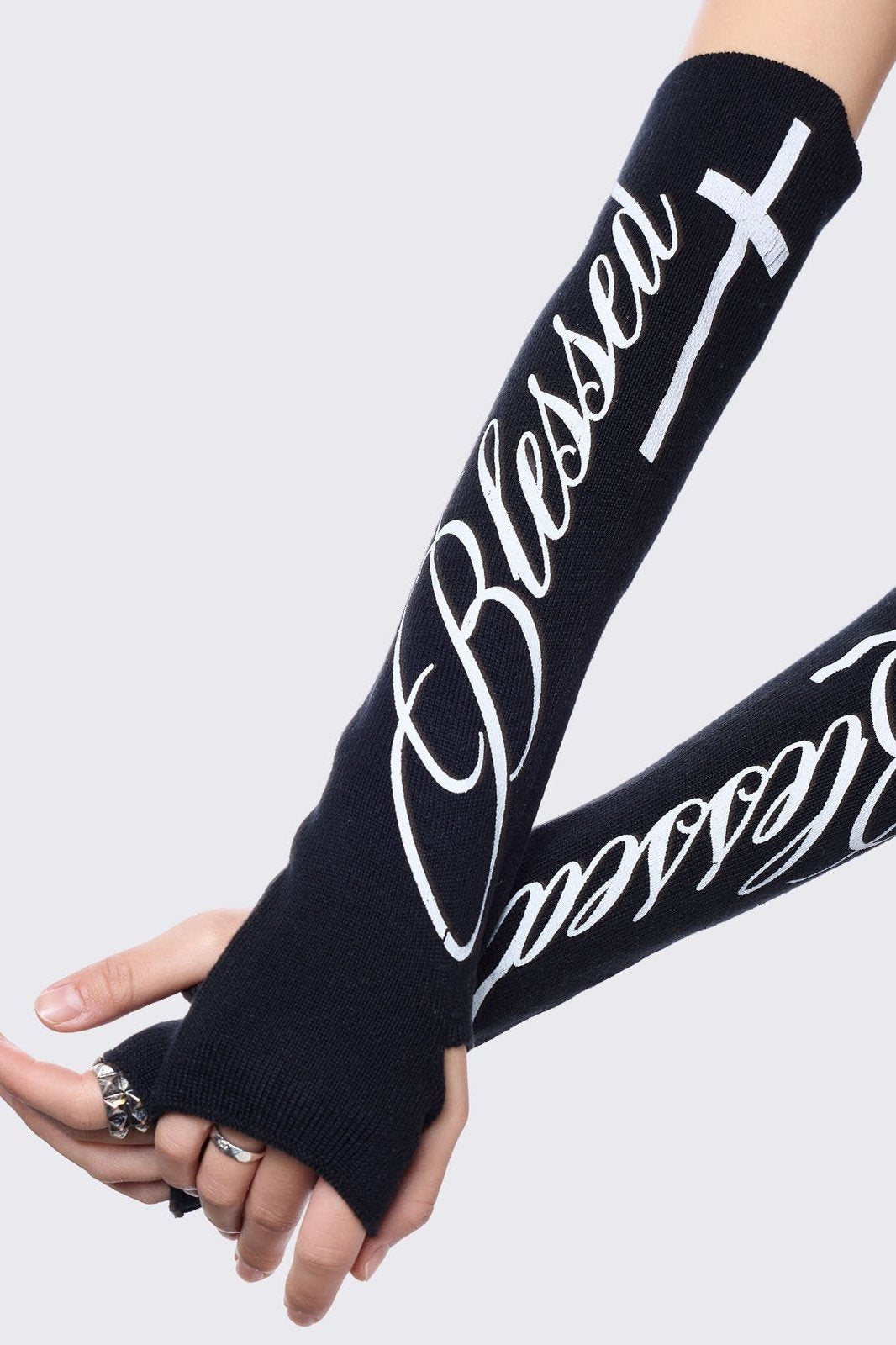 Black knitted arm warmers with white "blessed" cross print.