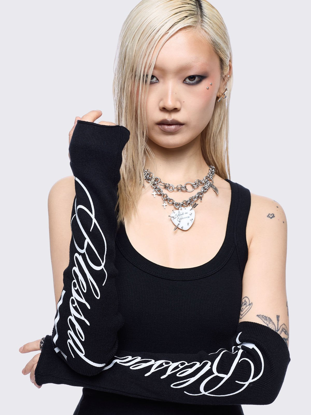 Black knitted arm warmers with white "blessed" cross print.