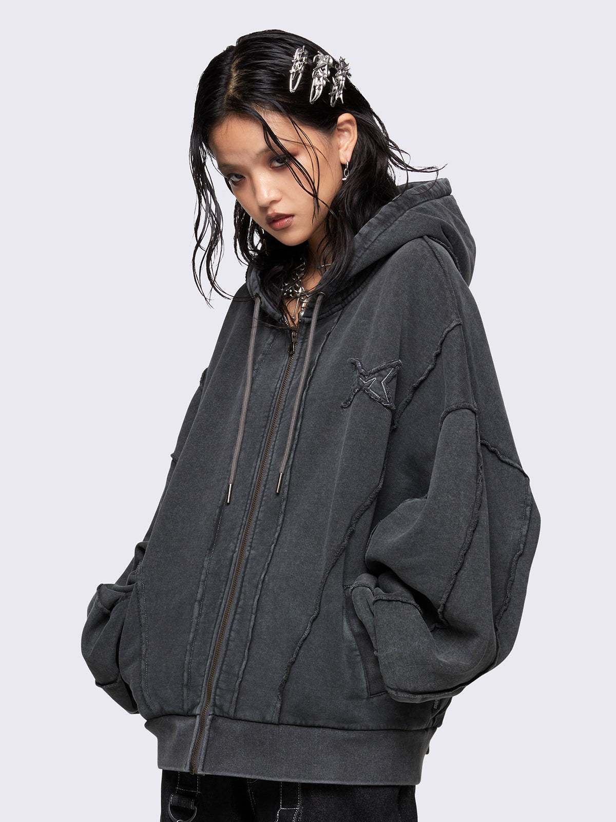 Washed grey oversized zip-up hoodie with exposed seam detailing, embroidered star patch on the chest, drawstring hood and ribbed cuffs and hem.