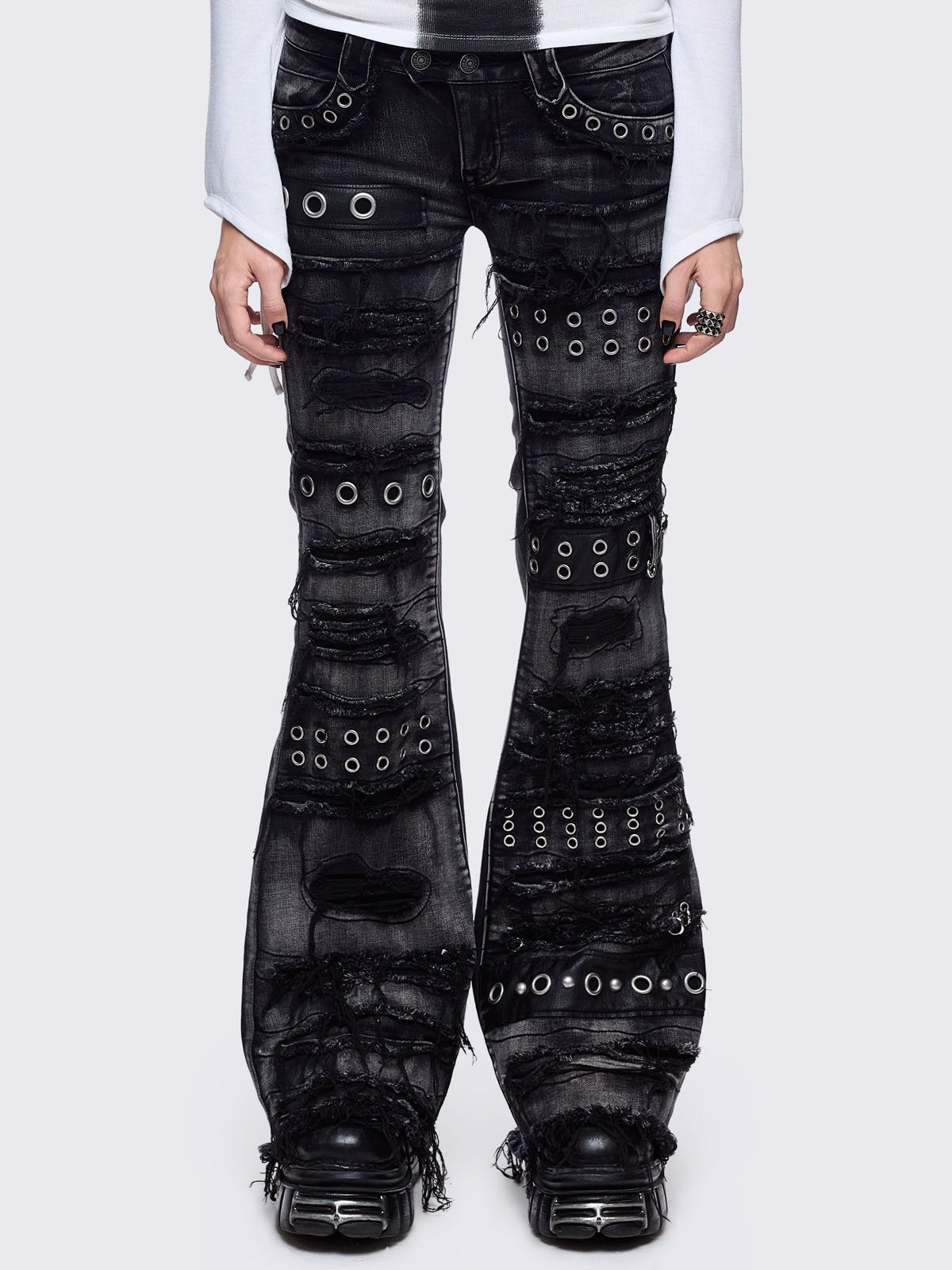Black washed flare jeans featuring heavy distressed and shedded, eyelet, piercing and stud details. 