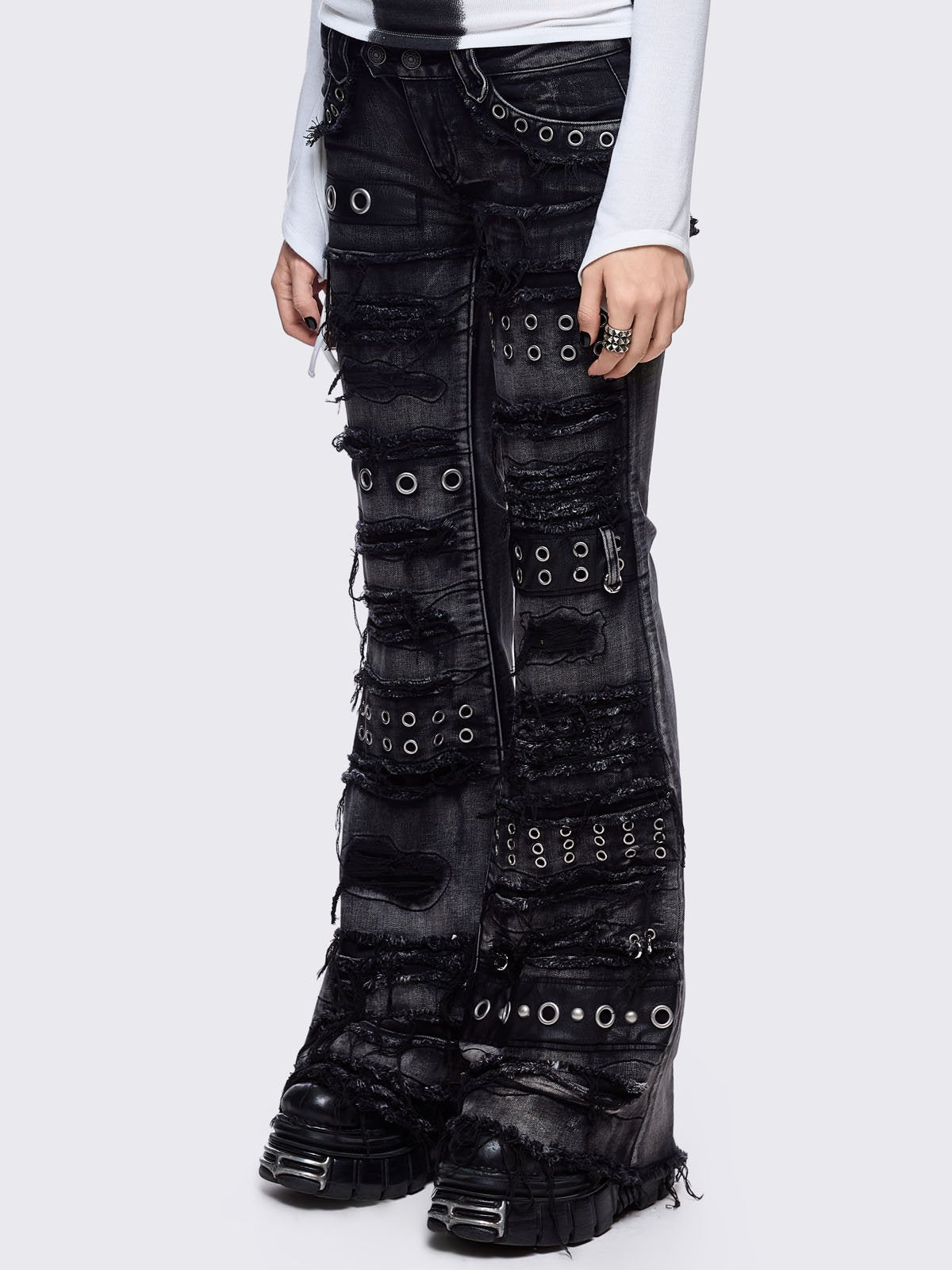 Black washed flare jeans featuring heavy distressed and shedded, eyelet, piercing and stud details. 