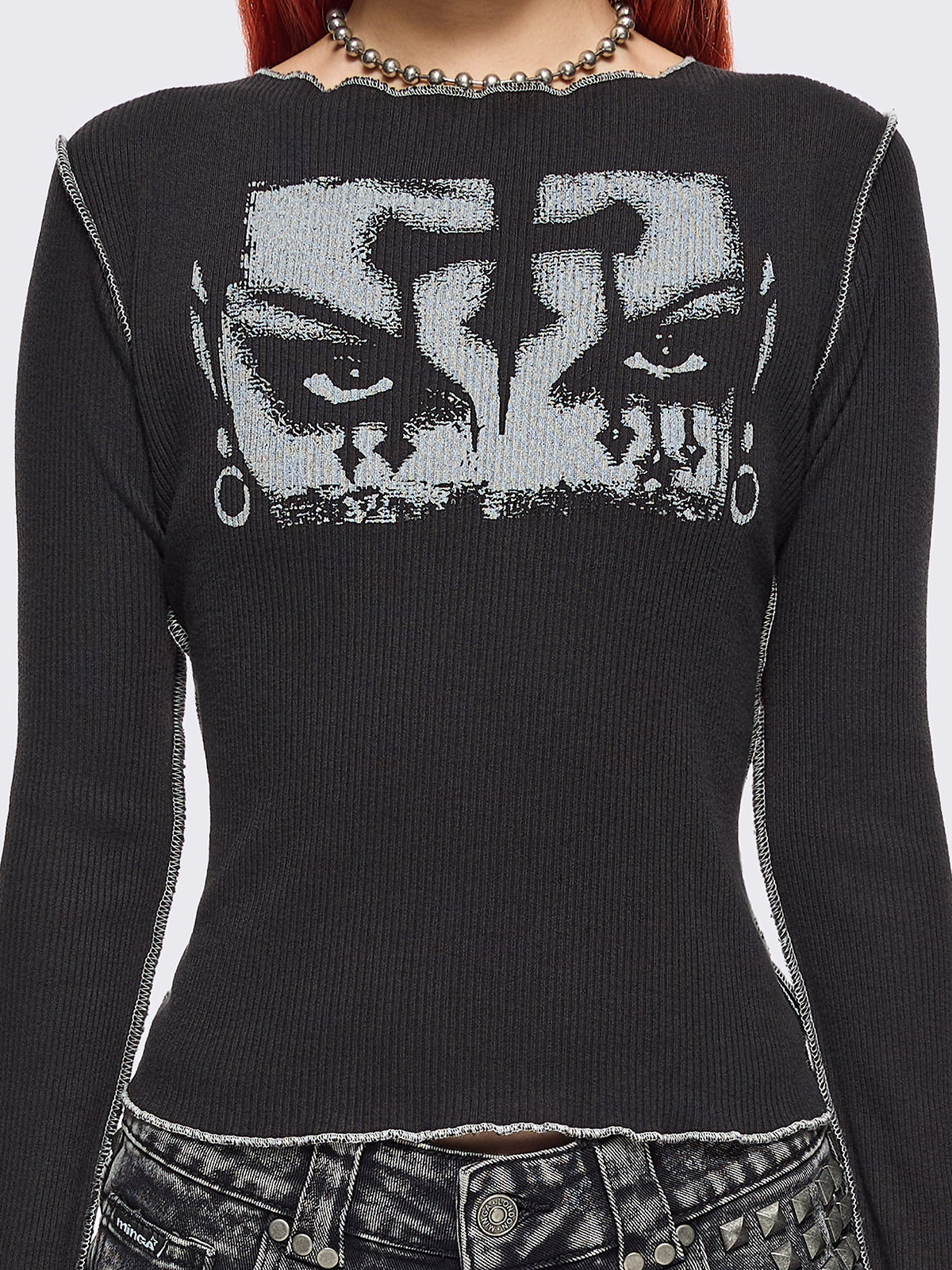 Black ribbed long sleeve top featuring a malefic eyes graphic front print, thumbhole cuffs and white reverse stitching. 