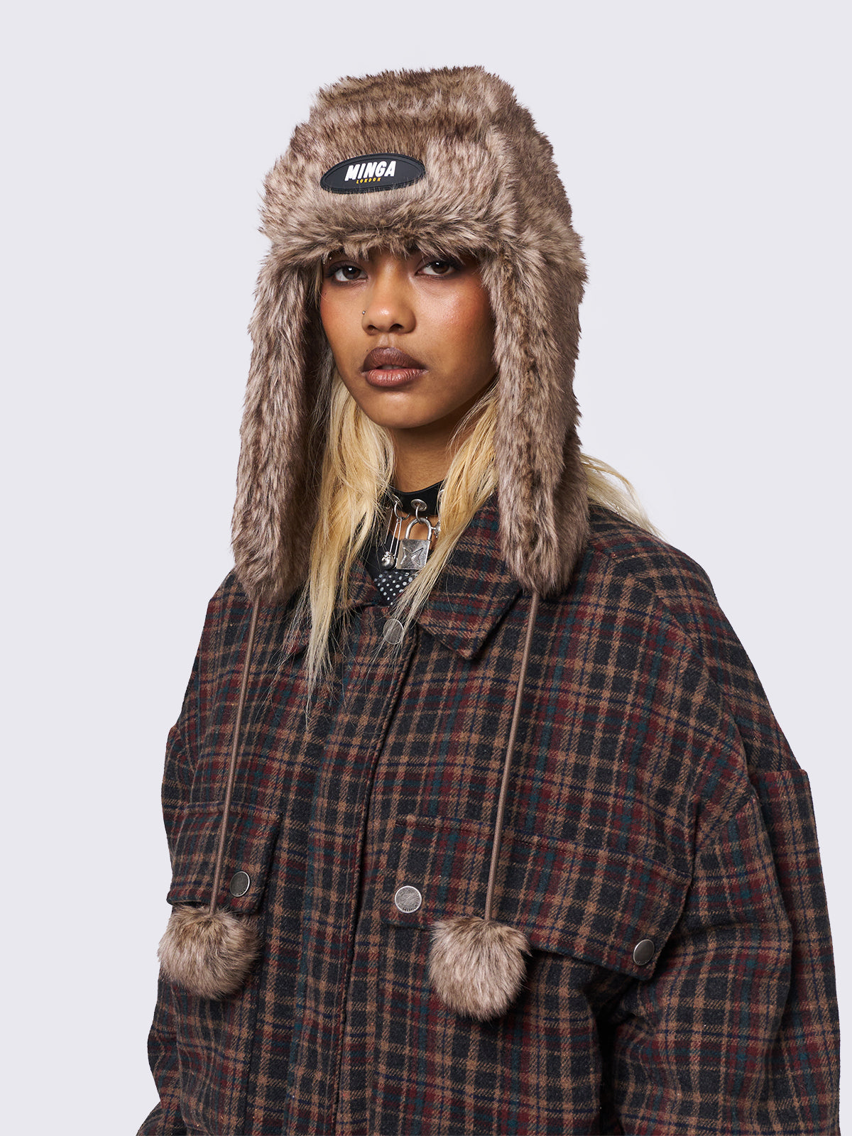 Faux fur trapper hat in brown with minga rubber logo detail and ear flaps