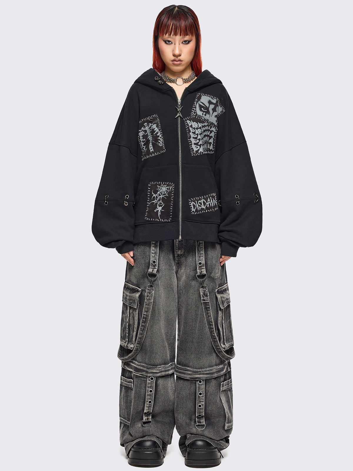 Black zip up hoodie jacket with white grunge print patches and eyelets with O-ring and piercing details.