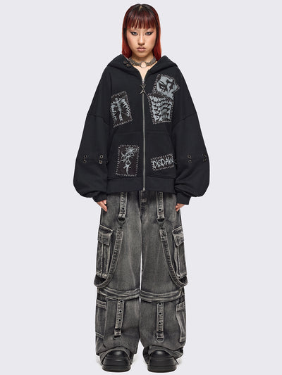 Black zip up hoodie jacket with white grunge print patches and eyelets with O-ring and piercing details.