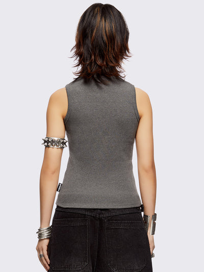 Sleeveless grey tank top with safety pins and piercing details. Grunge-style vibes. 