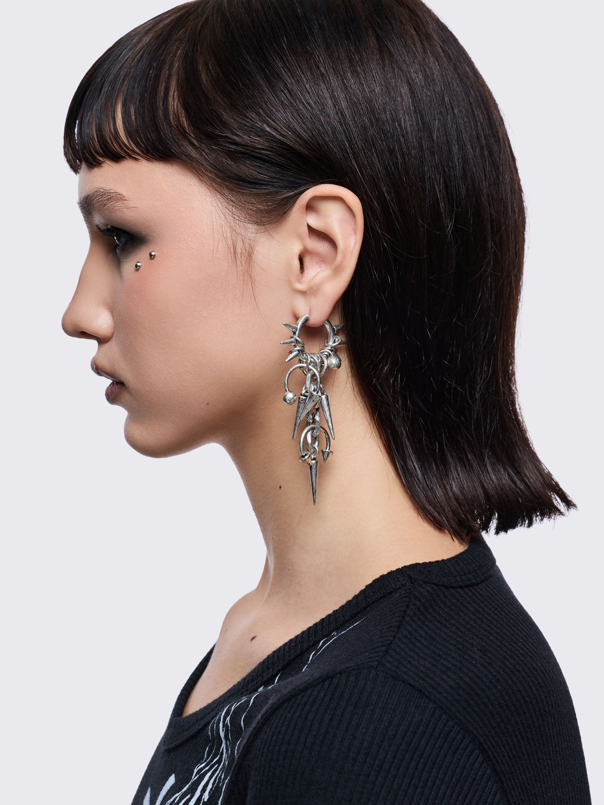 Silver chunky hoop earring with spike and piercing pendants.