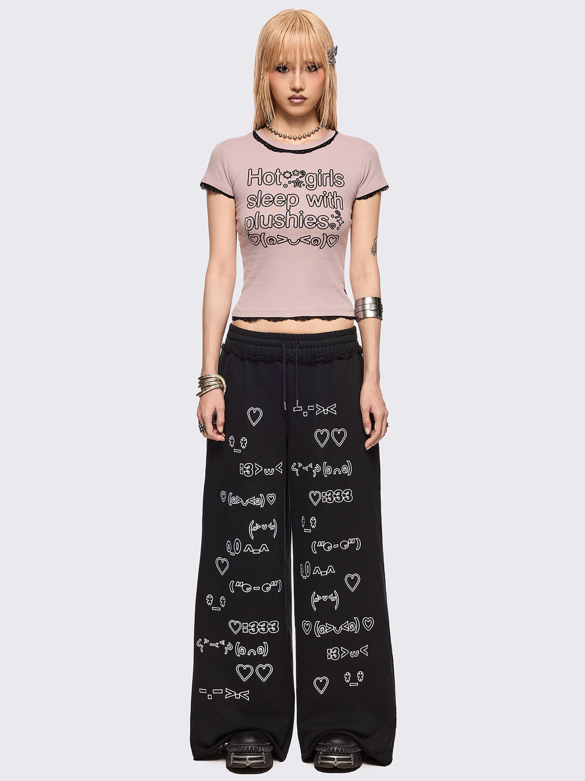 Baby pink graphic baby tee with "Hot girls sleep with plushies" graphic front print and black lace trims at seams.