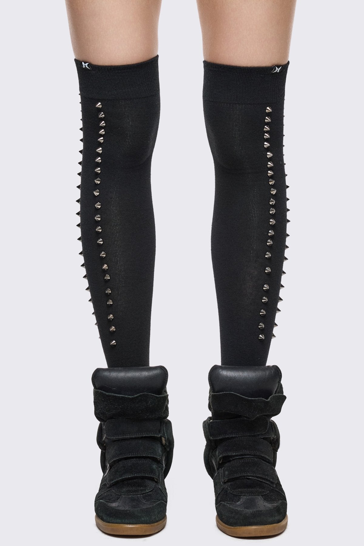 Black thigh-high socks in stretchy knit with silver spike details, grunge Y2K aesthetic.